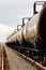 Black railroad tanker cars on a railroad siding, waiting to be filled with oil.