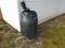 Black rain barrel with gutter downspout and hose