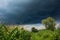 Black rain cloud in the sky over a green field. Pure nature landscape. Summer rainy days