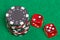 Black and red poker chips and dice on a green felt