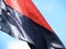 Black and red satin banner flying against the blue sky