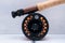 Black reel with orange fishing line on fishing rod close up on a light background