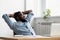 Black relaxed worker sitting on chair looking at window