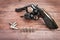 Black revolver gun with bullets isolated on wooden background