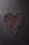 Black rice in heart shape on a black stone background with water droplets