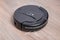 black Robot vacuum cleaner cleaning dust on tile floors. Modern smart cleaning technology housekeeping