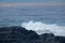 BLACK ROCK WITH WHITE SURF AND LAYER OF DISCOLOURED WATER