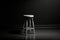 In a black room, a solitary white stool stands like a beacon of contrast, creating an intriguing visual composition