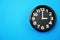 Black round clock showing five o`clock on blue background