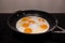 In a black round frying pan 6 fried eggs