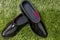 Black rubber galoshes lay on a background of green grass