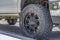 Black rubber wheel of a silver vehicle parked on the road on a sunny day