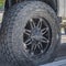 Black rubber wheel of a silver vehicle parked on the road on a sunny day