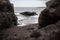 Black sand beach hidden between blurred volcanic rocks. Dramatic landscape