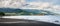 Black sand beach near by the town Ende. The landscape is remarkable with the mountains, Clouds and light in background, Ende, East