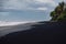 Black sand beach with ocean in Balian, Bali. Beach with palms and cloudy sky