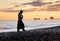 Black-sand beach at sunset. Young woman walking.