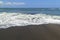 Black sand volcanic beach and white waves of ocean in Bali, Indonesia