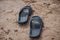 Black sandals on the beach sand