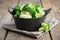 Black saucepan with cooked broccoli and cauliflower on wooden table