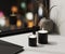 Black scented candle with aroma reed diffuser and vase with blured night city lights on background, home aromatic candles,