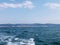 Black sea surface summer wave background. View from yacht. Exotic seascape with clouds and town on horizon. Sea nature tranquility