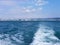Black sea surface summer wave background. View from yacht. Exotic seascape with clouds and town on horizon. Sea nature tranquility