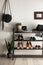 Black shelving unit with shoes and accessories near white wall in hall