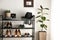 Black shelving unit with shoes and accessories near white wall in hall