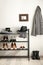 Black shelving unit with shoes and accessories near white wall in hall