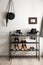 Black shelving unit with shoes and accessories near white wall in hall