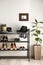 Black shelving unit with shoes and accessories near white wall in hall