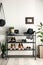 Black shelving unit with shoes and accessories near white wall in hall