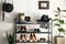 Black shelving unit with shoes and different accessories near white wall in hall