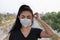 A Black shirt woman standing on putting on a respirator N95 mask to protect from airborne respiratory diseases as the flu covid-19