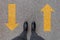 Black shoes standing on the asphalt concrete floor with two yellow arrows. Feet shoes walking in outdoor. Youth Selphie hipster