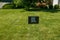 Black sign with blue writing on a green grass lawn that says black lives matter