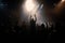 Black silhouette of a huge crowd of cheering people in front of a rock stage with soft bokeh lights created with generative AI