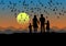 Black silhouette, parents, son and daughter are standing at sunset. There are birds flying in the sky