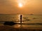 Black silhouette of woman walking on  beach as sun sets over sea.  Observing sunset on  beach