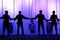 Black silhouettes of people holding hands on the stage of the theater in front of the ropes