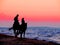 Black silhouettes in the twilight sunset light of horses and a girl with a man riders on the seashore, romantic date