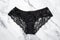 Black silk panty with lace on light marble background. Female erotic panties. Women`s underpants. Woman elegance underwear