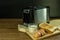 Black and silver electric micro oven with toast, fresh eggs and glass of milk on brown wooden and black blackground