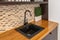 Black sink in the kitchen. Modern kitchen in the attic with black kitchen cabinets