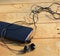 Black smartphone and headphones on a wooden light brown background