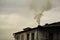 the black smoke comes from chimney of a house against gray sky, heating with coal in winter. environmental problem of smog in Besk