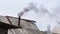 Black smoke coming out from rustic bathhouse chimney steel pipe, the concept of heating with low quality coal or rags