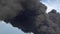 Black smoke rises above the buildings. A big chemical fire at a factory building. Thick black smoke covers the sky.
