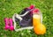 Black sneakers, dumbbells, glass of orange juice and fresh oranges on fresh green grass